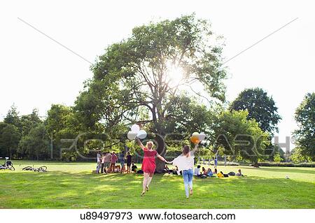 Rear view of two young women dancing with balloons at park party View Large Photo Image Stock Image - Rear view of two young women dancing with balloons at park party. Fotosearch