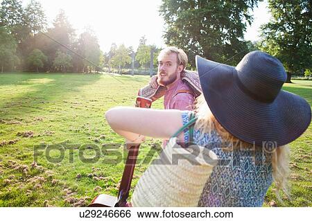 Stock Photograph - Romantic young couple carrying rug for picnic in park. Fotosearch