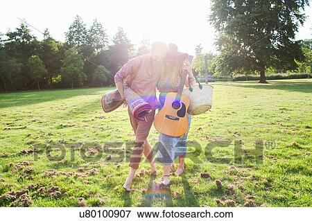 Romantic young couple carrying rug in park View Large Photo Image Stock Photo - Romantic young couple carrying rug in park. Fotosearch