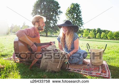 Romantic young couple playing acoustic guitar in park View Large Photo Image Stock Photo - Romantic young couple playing acoustic guitar in park. Fotosearch