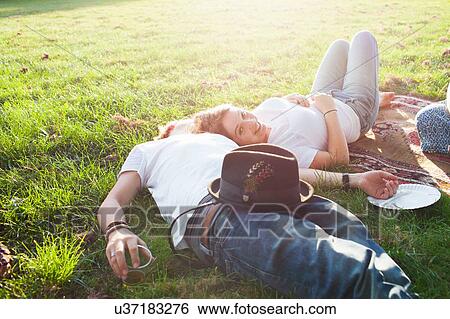 Stock Photograph - Romantic young couple relaxing at party picnic in park. Fotosearch