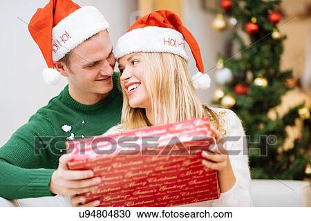 Stock Image - Romantic young couple sharing christmas present. Fotosearch
