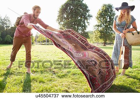 Romantic young couple spreading rug for picnic in park View Large Photo Image Stock Photo - Romantic young couple spreading rug for picnic in park. Fotosearch