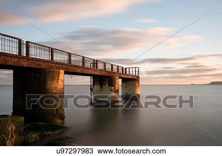 Rusting pier at dusk, Overcombe Beach, Dorset, UK View Large Photo Image Stock Image - Rusting pier at dusk, Overcombe Beach, Dorset, UK. Fotosearch