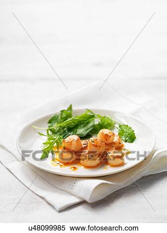 Stock Photography - Scallops with chilli and coriander served with green salad leaves. Fotosearch