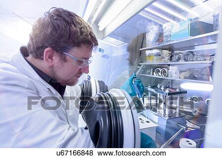 Scientist assembling lithium ion test batteries in glove chamber in battery research facility View Large Photo Image Stock Photo - Scientist assembling lithium ion test batteries in glove chamber in battery research facility. Fotosearch