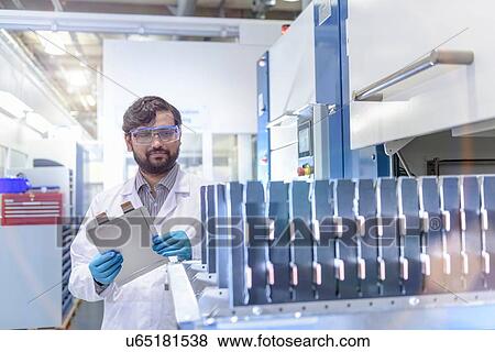 Stock Photo - Scientist with lithium ion pouch cell manufacture machine in battery research facility. Fotosearch