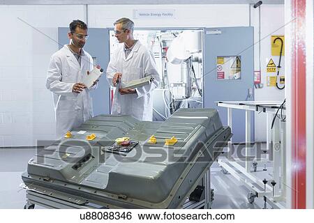 Stock Photograph - Scientists inspecting lithium ion car battery components in battery research facility. Fotosearch