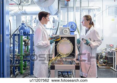 Stock Image - Scientists testing lithium car battery with electric motor car in battery research facility. Fotosearch