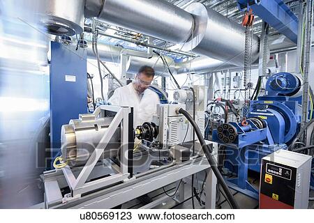 Stock Image - Scientists testing lithium car battery with electric motor car in battery research facility. Fotosearch