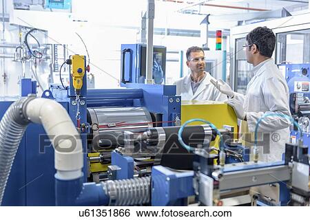 Stock Photograph - Scientists with lithium ion battery production line in battery research facility. Fotosearch