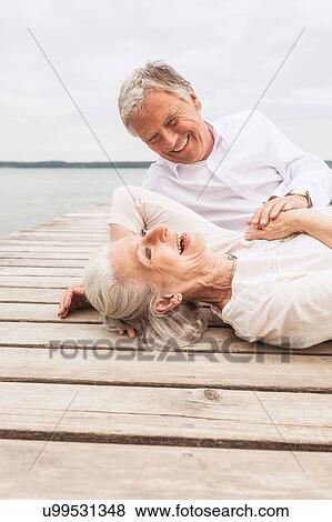 Senior couple relaxing on pier, laughing View Large Photo Image Stock Photo - Senior couple relaxing on pier, laughing. Fotosearch