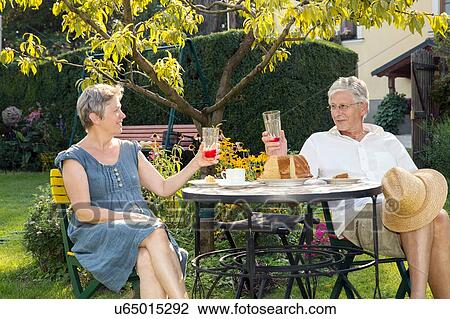 Senior couple, sitting at table in garden, enjoying drink View Large Photo Image Stock Image - Senior couple, sitting at table in garden, enjoying drink. Fotosearch