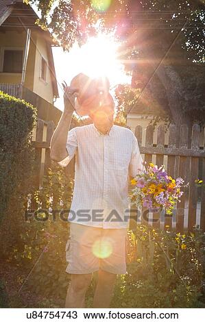 Stock Image - Senior man in garden, holding bunch of fresh cut flowers. Fotosearch
