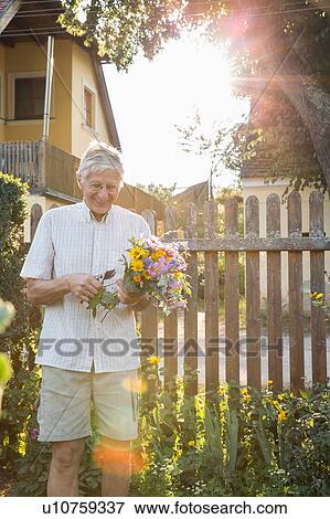 Stock Photo - Senior man in garden, holding bunch of fresh cut flowers. Fotosearch