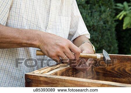 Stock Photo - Senior man making wooden crate in garden, mid section. Fotosearch