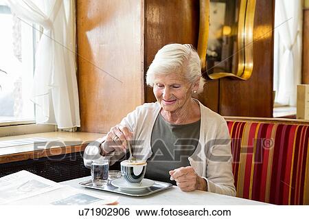 Senior woman sitting in cafe, stirring coffee View Large Photo Image Stock Photograph - Senior woman sitting in cafe, stirring coffee. Fotosearch