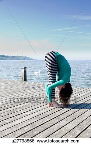Side view of mature woman on pier by ocean bending over holding ankles View Large Photo Image Stock Photograph - Side view of mature woman on pier by ocean bending over holding ankles. Fotosearch