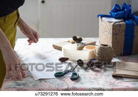 Side view of mid adult woman wrapping gift at table View Large Photo Image Stock Photograph - Side view of mid adult woman wrapping gift at table. Fotosearch