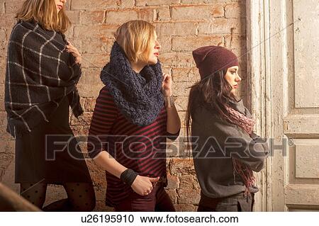 Side view of women wearing knitwear standing on stairs in front of brick wall looking away View Large Photo Image Stock Image - Side view of women wearing knitwear standing on stairs in front of brick wall looking away. Fotosearch