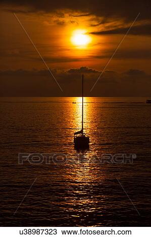 Stock Image - Silhouetted yacht at sunset, Camogli, Liguria, Italy. Fotosearch