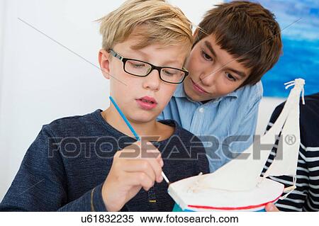 Teenage boy and brother painting toy boat at kitchen table View Large Photo Image Stock Photography - Teenage boy and brother painting toy boat at kitchen table. Fotosearch