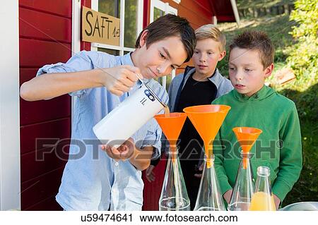 Teenage boy and brothers pouring fresh orange juice to sell at roadside View Large Photo Image Stock Image - Teenage boy and brothers pouring fresh orange juice to sell at roadside. Fotosearch