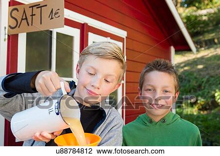 Stock Image - Two brothers pouring fresh orange juice to sell at roadside. Fotosearch