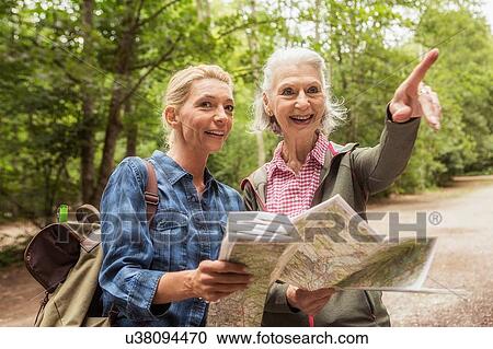 Stock Image - Two female friends on hiking trail, looking at map, pointing. Fotosearch
