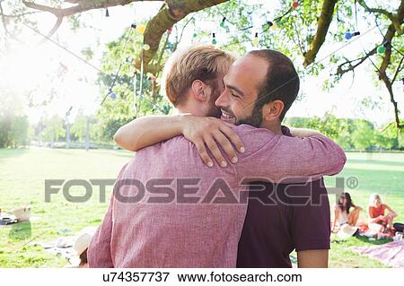 Stock Photo - Two young men hugging each other at party in park. Fotosearch