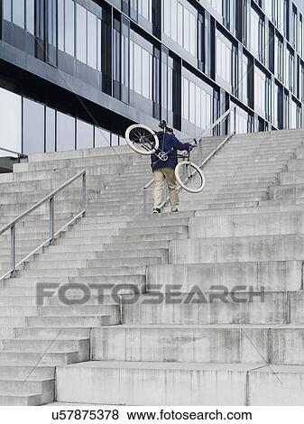 Urban cyclist carrying bicycle ascending stairway View Large Photo Image Stock Photo - Urban cyclist carrying bicycle ascending stairway. Fotosearch