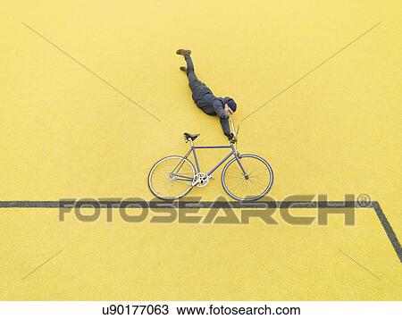 Urban cyclist doing illusionary stunt against yellow wall View Large Photo Image Stock Image - Urban cyclist doing illusionary stunt against yellow wall. Fotosearch