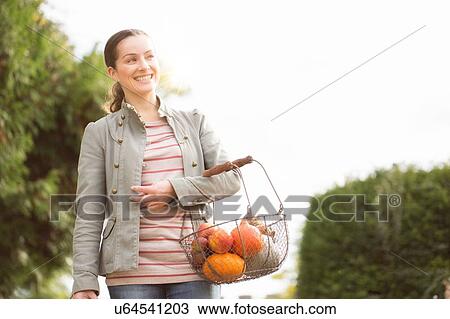 Woman carrying basket of organic fruit and veg View Large Photo Image Stock Image - Woman carrying basket of organic fruit and veg. Fotosearch