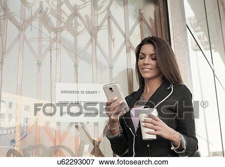 Woman outdoors, using smartphone, holding coffee cup View Large Photo Image Stock Photo - Woman outdoors, using smartphone, holding coffee cup. Fotosearch