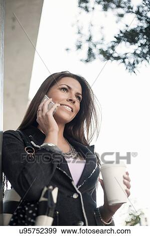 Woman outdoors, using smartphone, holding coffee cup View Large Photo Image Stock Photo - Woman outdoors, using smartphone, holding coffee cup. Fotosearch