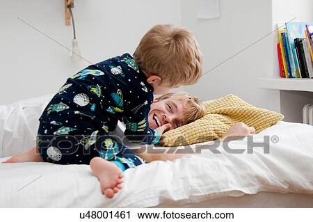 Stock Image - Young boy waking up father n bed. Fotosearch