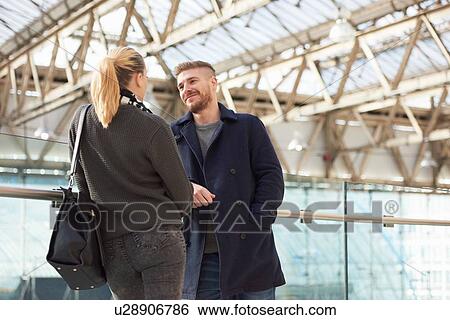 Stock Photograph - Young couple at train station, face to face, smiling. Fotosearch