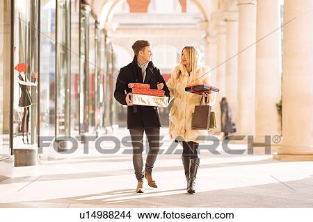 Picture - Young couple carrying xmas gifts strolling in Covent Garden, London, UK. Fotosearch