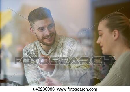 Stock Image - Young couple in cafe, smiling. Fotosearch