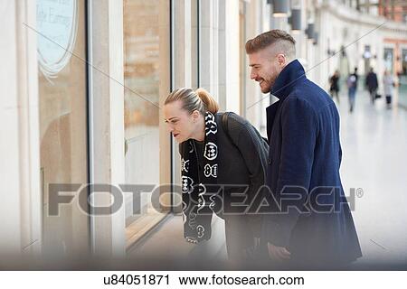 Young couple looking in store window, smiling View Large Photo Image Stock Image - Young couple looking in store window, smiling. Fotosearch