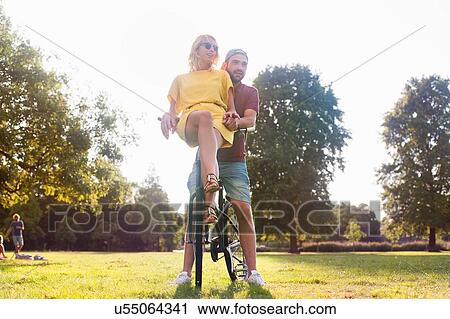 Young couple on bicycle at sunset party in park View Large Photo Image Stock Image - Young couple on bicycle at sunset party in park. Fotosearch