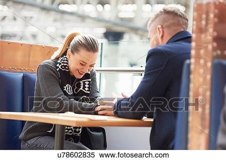 Stock Photography - Young couple sitting at cafe, holding hands, laughing. Fotosearch