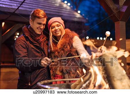 Young couple toasting marshmallows at xmas festival in Hyde Park, London, UK View Large Photo Image Stock Image - Young couple toasting marshmallows at xmas festival in Hyde Park, London, UK. Fotosearch