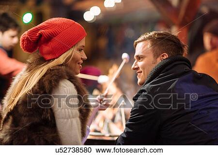 Stock Image - Young couple toasting marshmallows at xmas festival in Hyde Park, London, UK. Fotosearch
