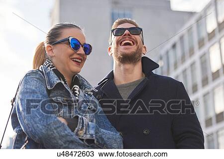 Stock Image - Young couple wearing sunglasses and warm clothing, outdoors. Fotosearch