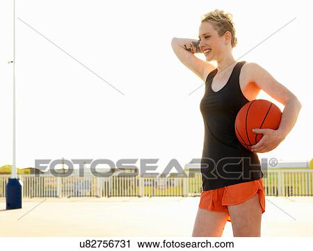 Stock Image - Young female basketball player in training in parking lot. Fotosearch