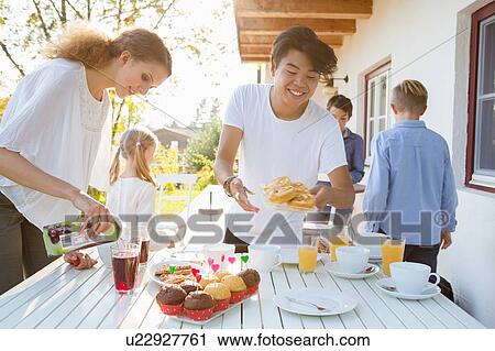 Young man and teenage girl preparing party table on patio View Large Photo Image Stock Image - Young man and teenage girl preparing party table on patio. Fotosearch