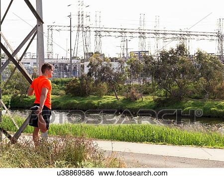 Young man beside river, exercising, stretching View Large Photo Image Stock Photograph - Young man beside river, exercising, stretching. Fotosearch