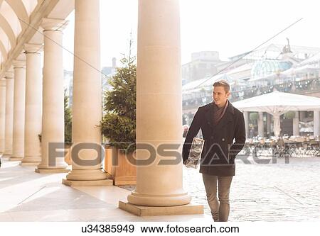 Stock Photo - Young man carrying xmas gift in Covent Garden, London, UK. Fotosearch