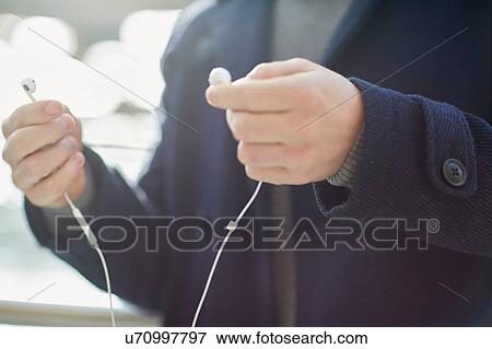Young man holding earphones, outdoors, mid section View Large Photo Image Stock Photo - Young man holding earphones, outdoors, mid section. Fotosearch